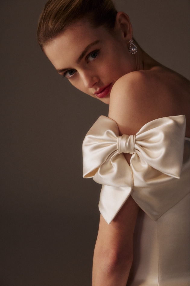 model in satin wedding dress with bows on upper arms
