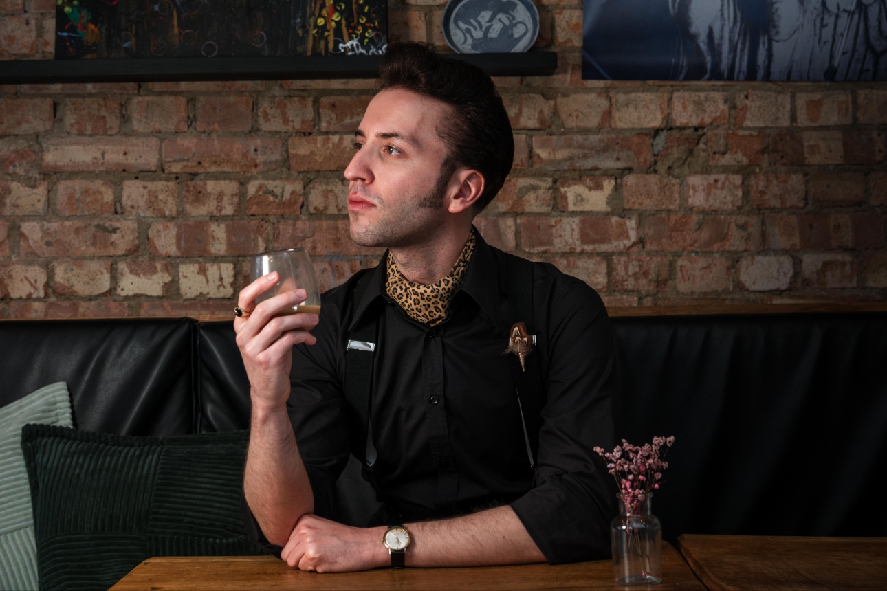 man sat down with leopard print accessories on black shirt  